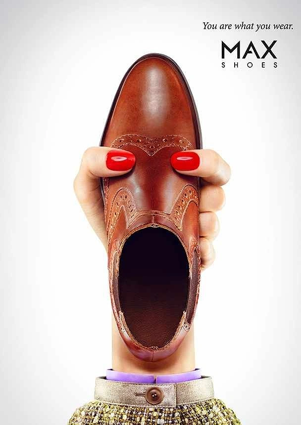 Fashion creative ad: Hand holding a brown brogue so it becomes a face, with red nails as eyes