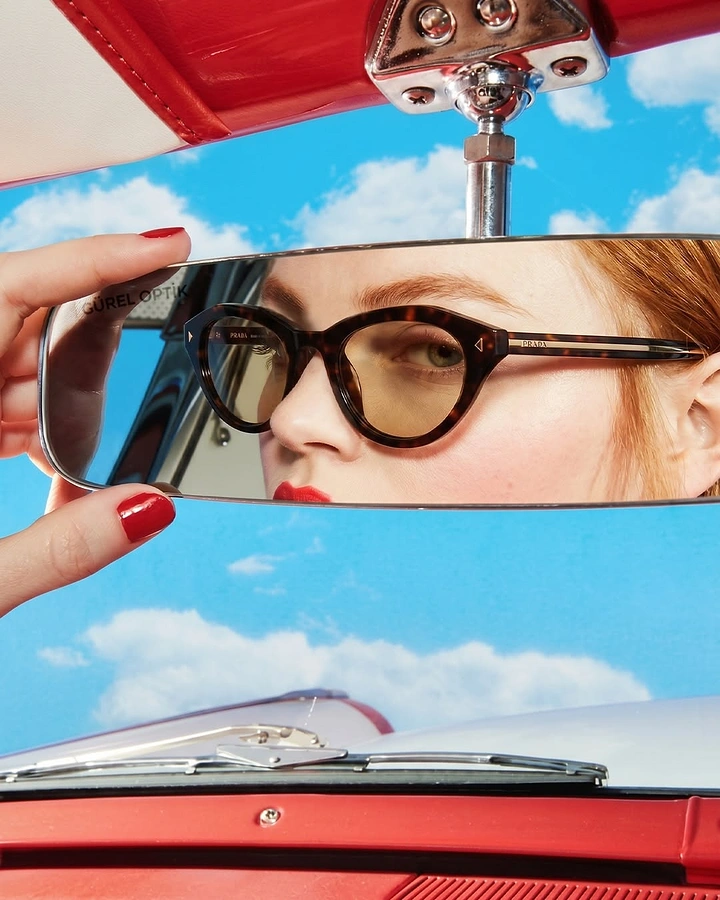 Creative ad: Woman in tortoiseshell cat-eye sunglasses reflected in a car rearview mirror