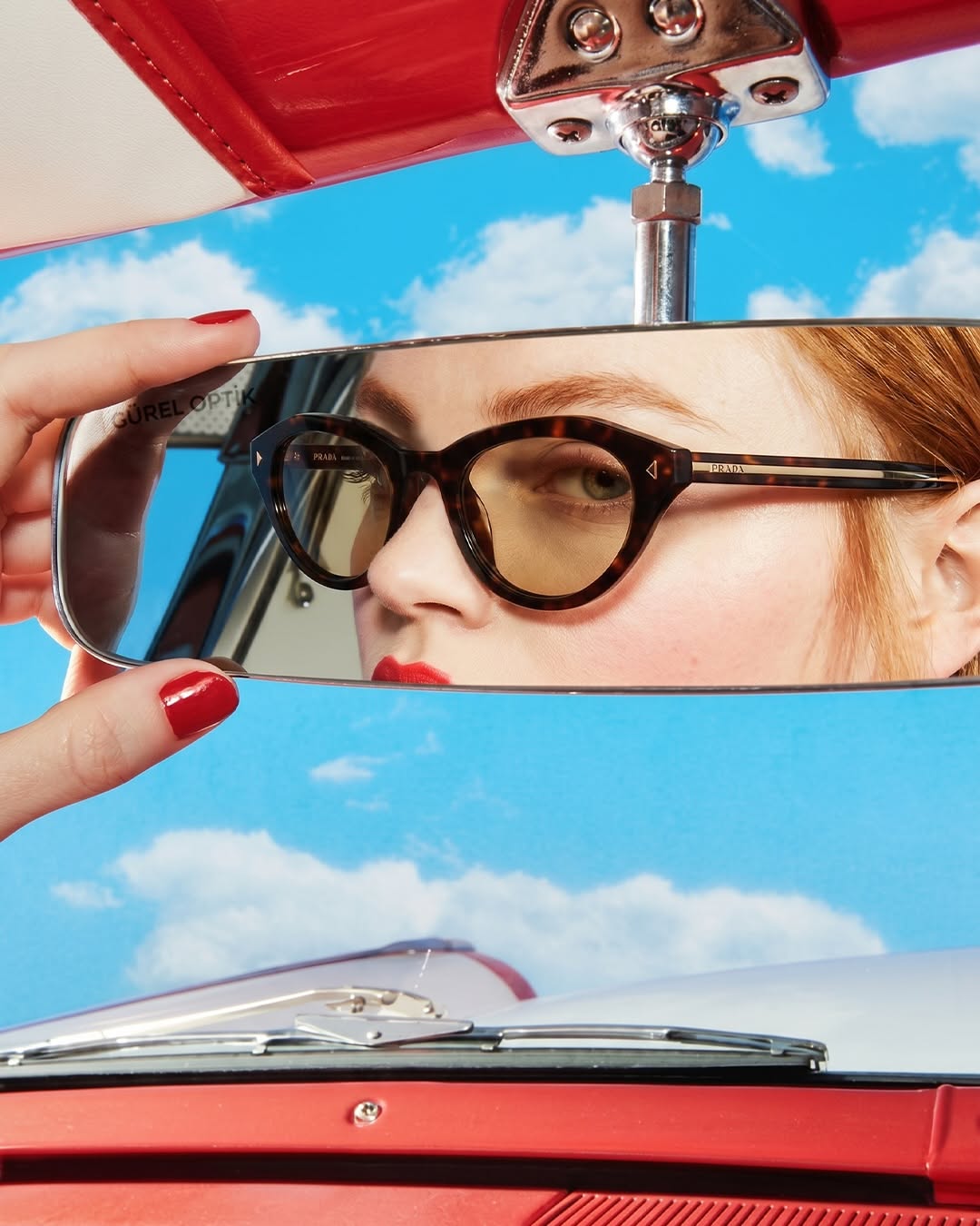 Carousel: Woman in tortoiseshell cat-eye sunglasses reflected in a car rearview mirror, slide 1