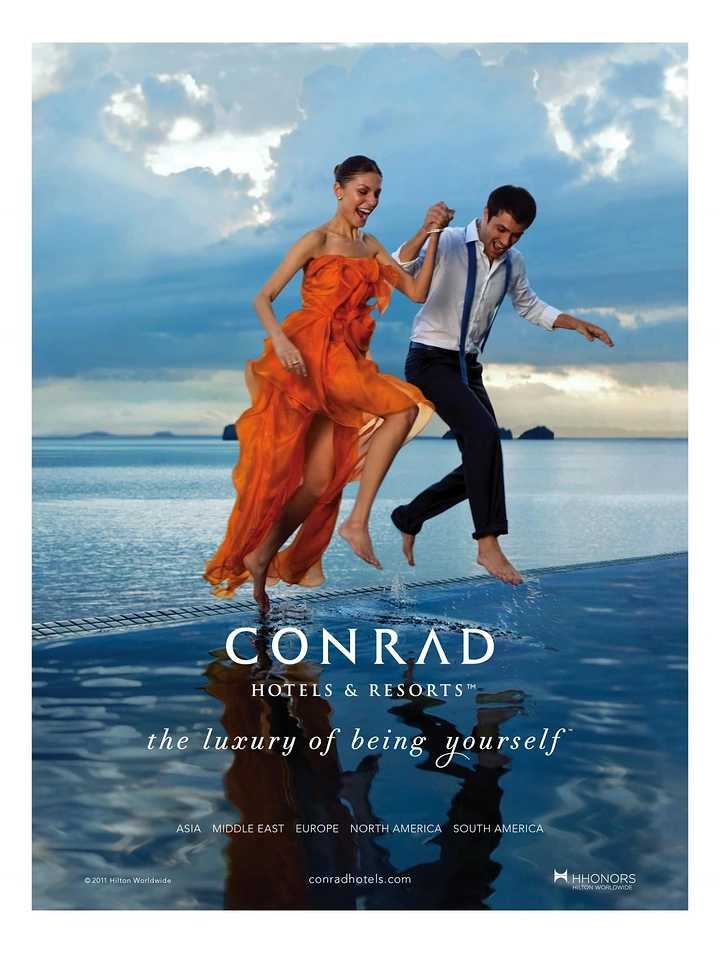 Creative ad: Couple in evening wear leaping barefoot across an infinity pool edge