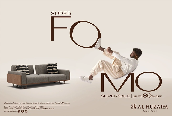 Creative ad: Man leaning back into giant letters beside a sofa