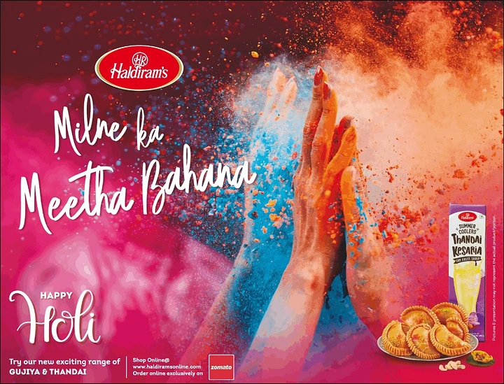 Holi creative ad: Two colour-covered hands meeting in a burst of gulal powder