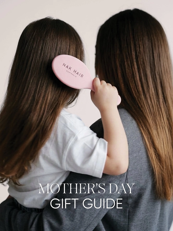 Mother's Day creative ad: Mother holding a child from behind while the child brushes her hair with a pink branded brush