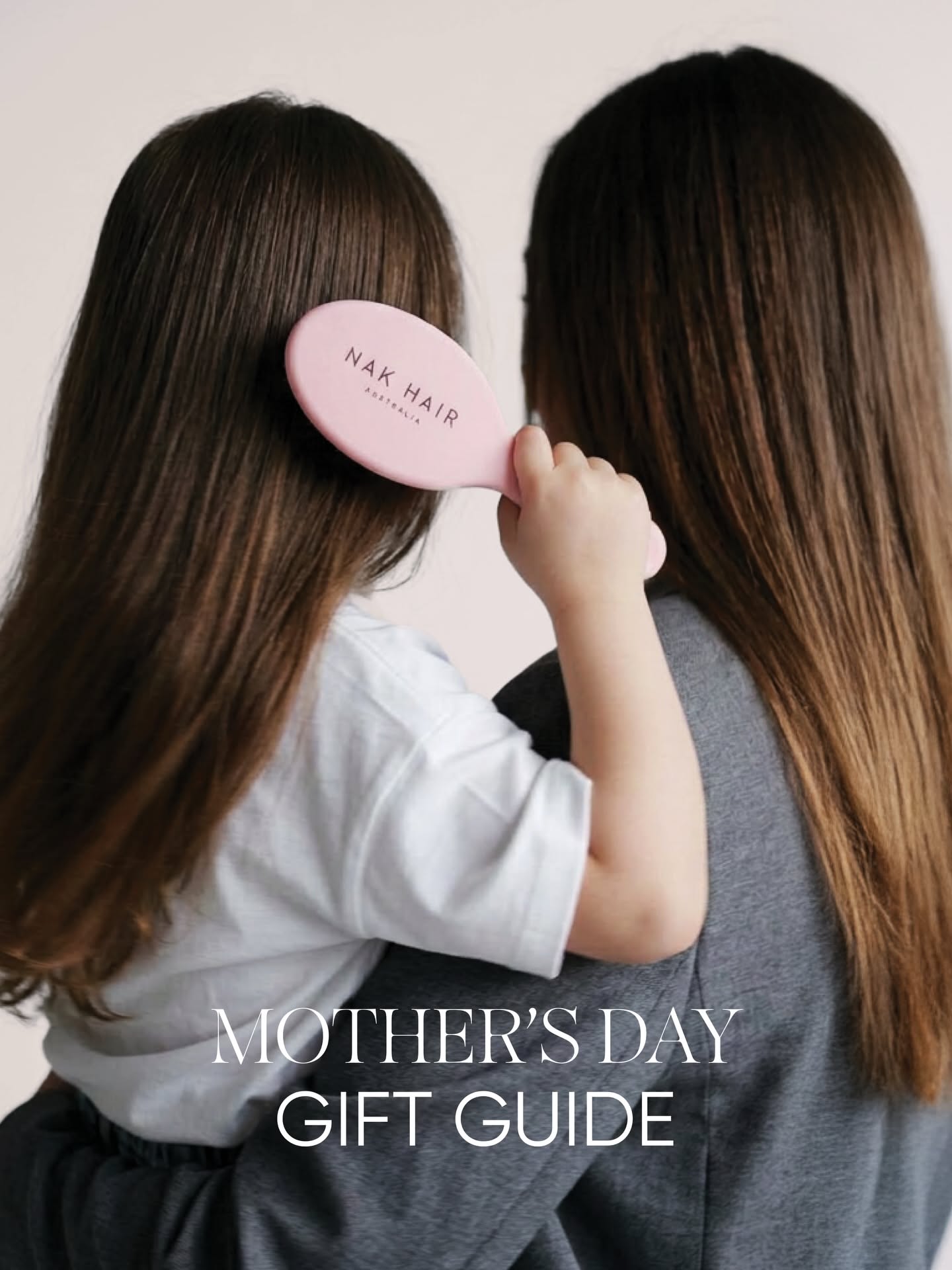 Mother's Day Carousel: Mother holding a child from behind while the child brushes her hair with a pink branded brush, slide 1