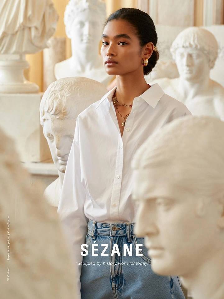 Creative ad: Model in white shirt and jeans among classical plaster busts