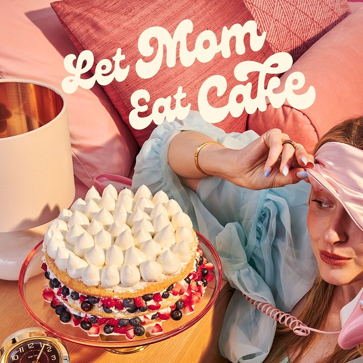 Mother's Day creative ad: Woman lounging in bed with a sleep mask beside a berry cream cake