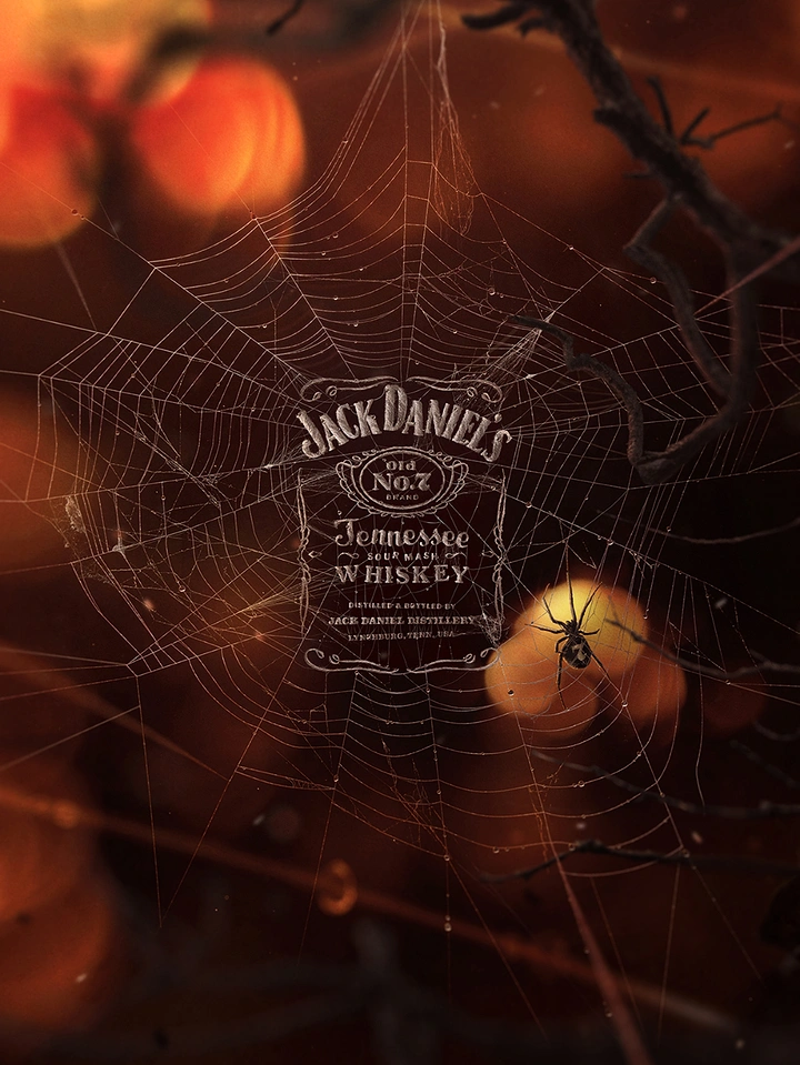 Halloween creative ad: Whiskey label woven into a dewy spider web