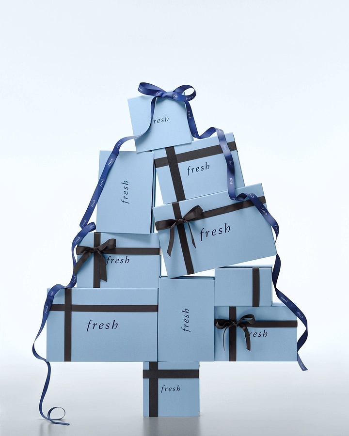 Christmas creative ad: Stacked pale-blue branded gift boxes forming a Christmas tree