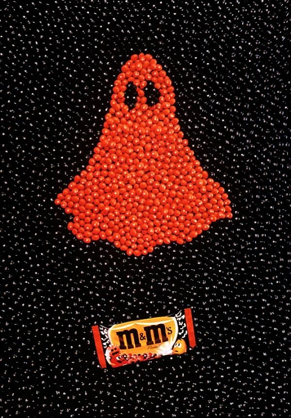 Halloween creative ad: Ghost shape made of orange candies on black candies