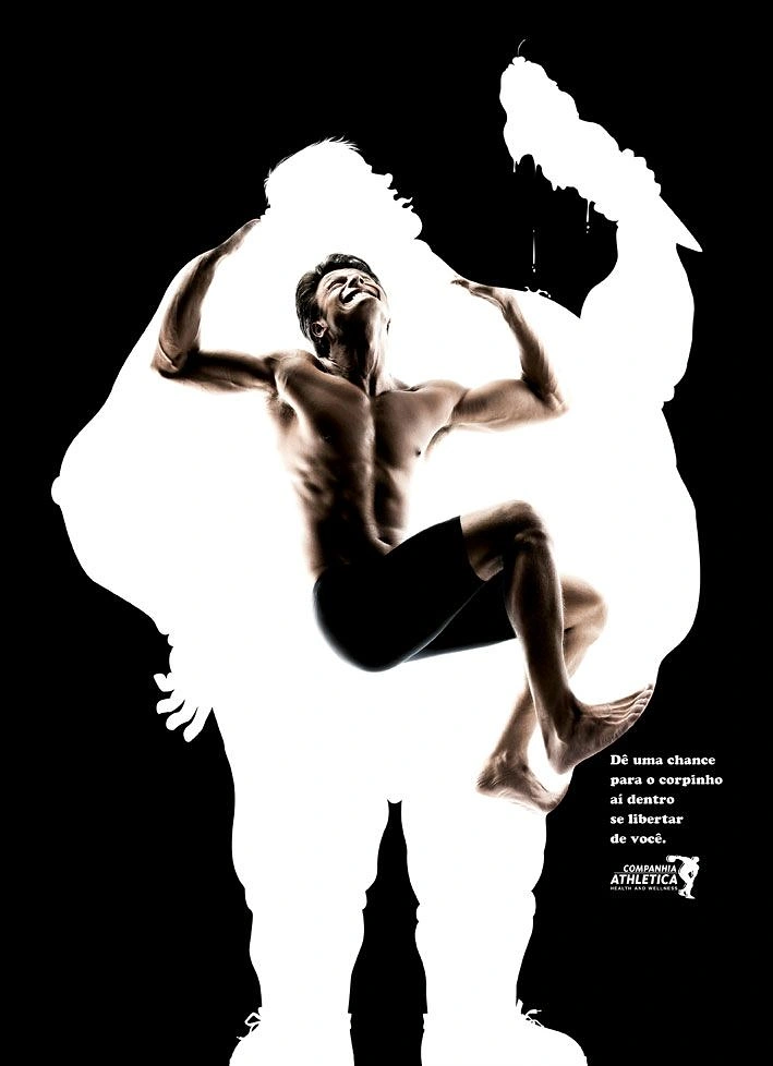 Gym & Fitness creative ad: Muscular man bursting out of a large white silhouette of an overweight person holding an ice cream