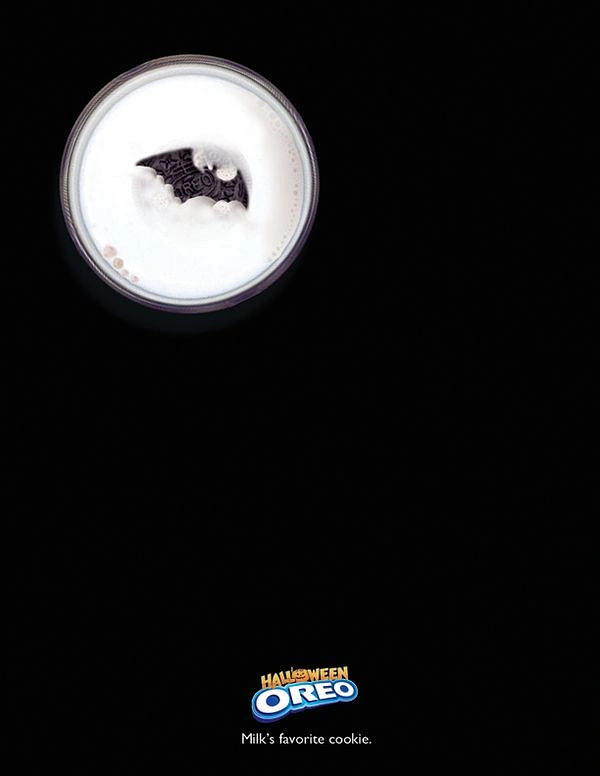 Halloween creative ad: Bat-shaped cookie in a glass of milk that looks like a moon