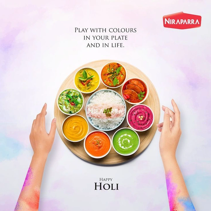 Holi creative ad: Top-down round platter of rainbow-coloured curry bowls with hands reaching in
