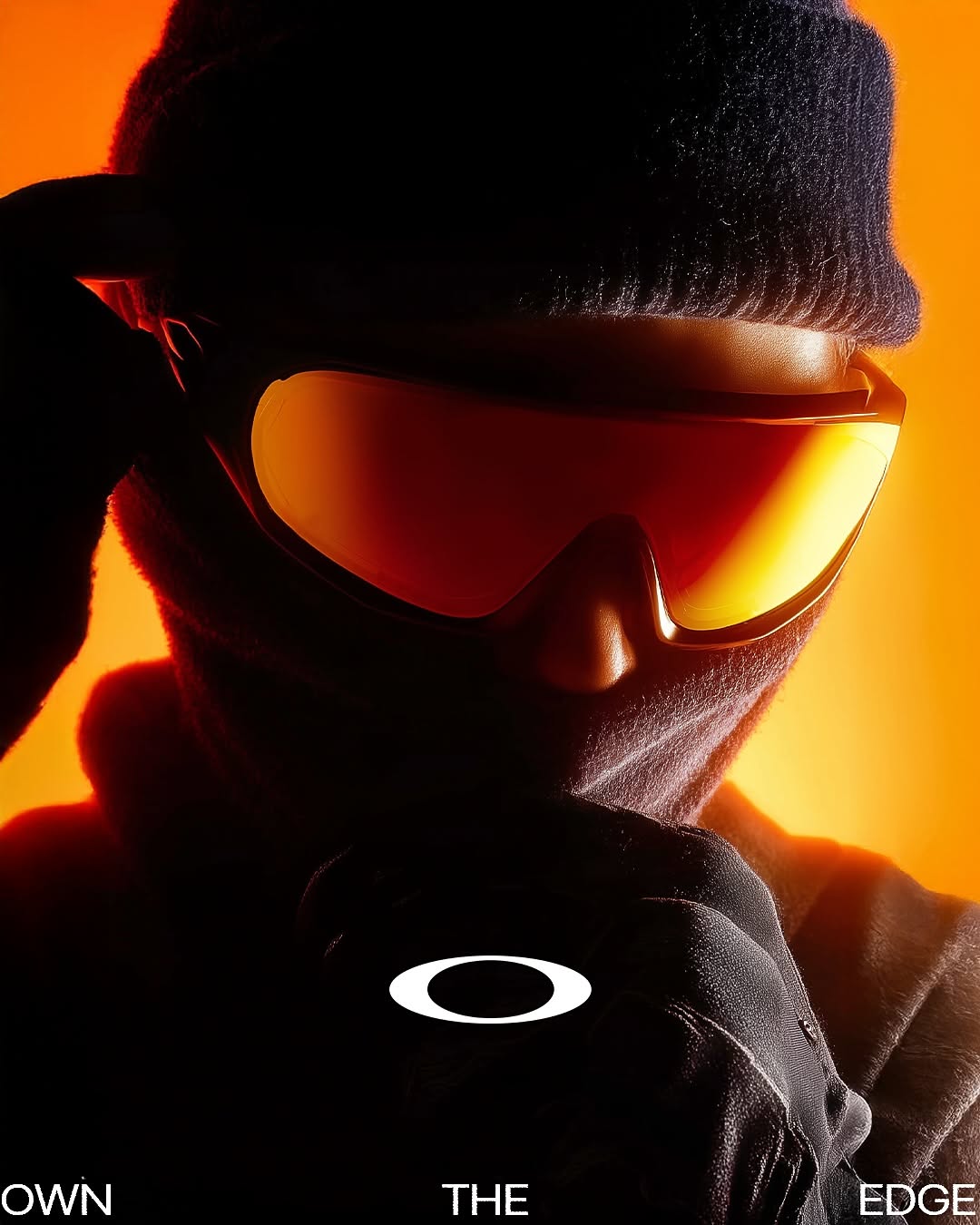 Carousel: Silhouetted figure in beanie and balaclava wearing mirrored orange wraparound shades, slide 1