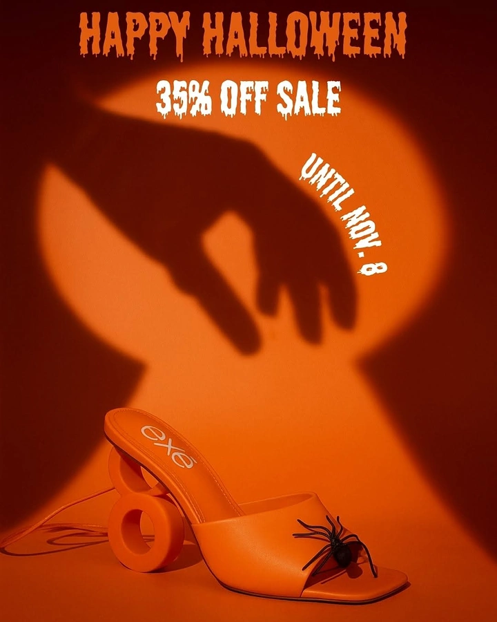 Halloween creative ad: Orange sculptural-heel mule with a toy spider, under a creeping hand shadow