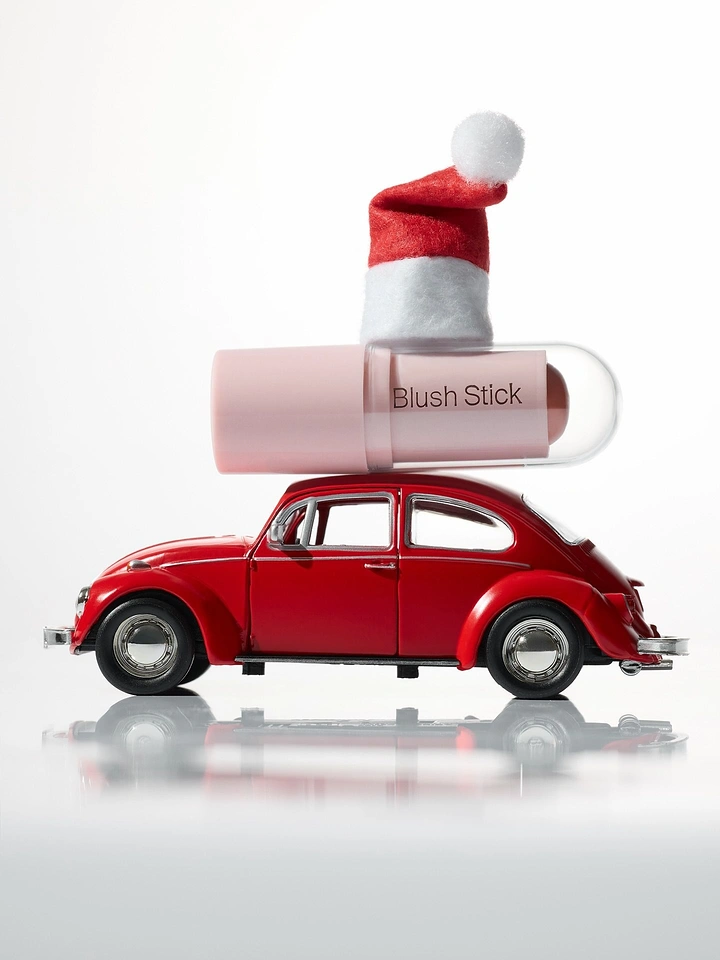 Christmas creative ad: Blush stick wearing a Santa hat on a red toy car