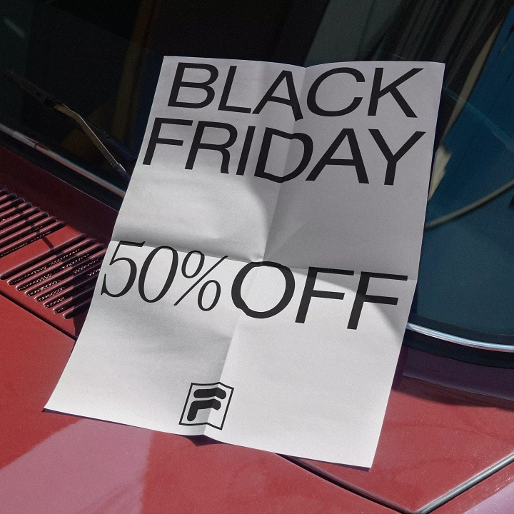 Black Friday creative ad: Creased paper flyer tucked under a red car's windshield wiper