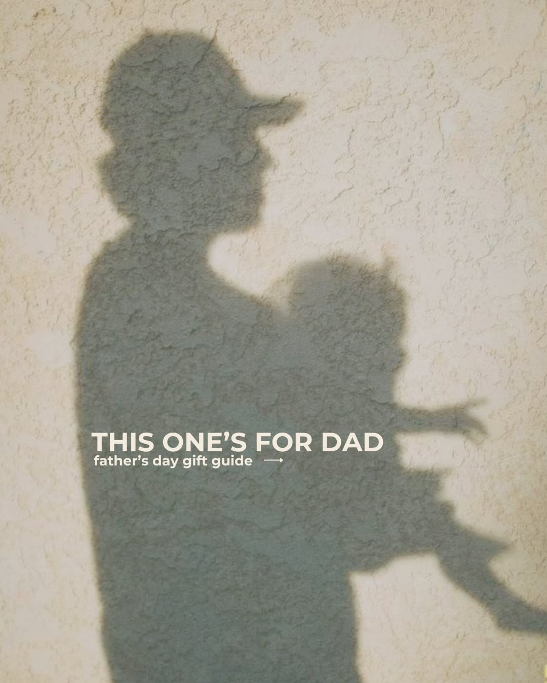 Shadow of a father in a cap holding a child on a wall