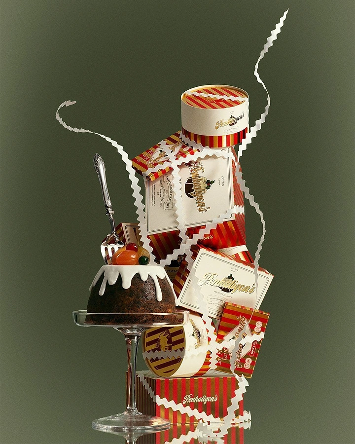 Christmas creative ad: Christmas pudding on a glass stand beside a tower of striped gift boxes