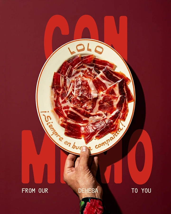 Restaurant & Cafe creative ad: Plate of thinly sliced Iberian ham held up by a hand from below