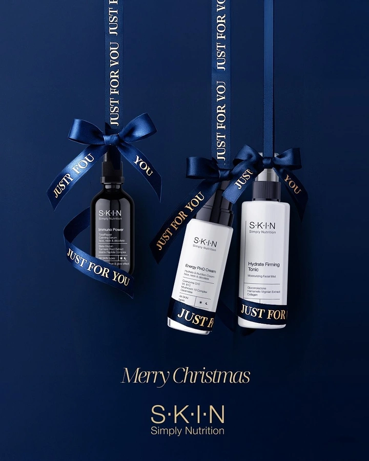 Christmas creative ad: Three skincare bottles hanging like ornaments from navy satin ribbons
