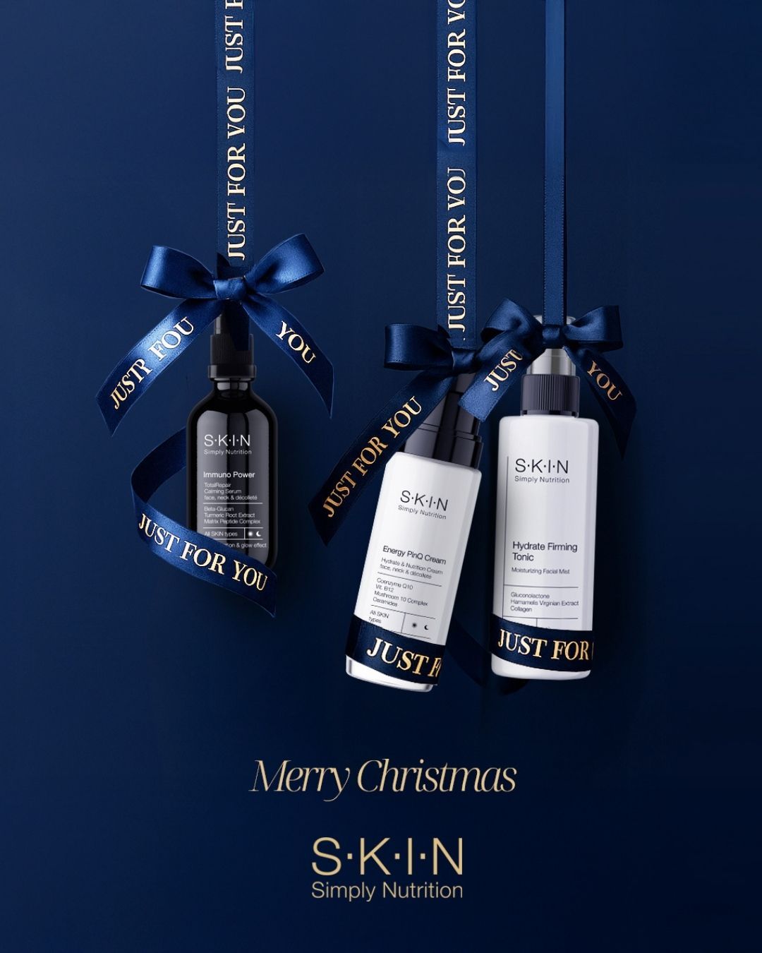 Christmas Instagram post: Three skincare bottles hanging like ornaments from navy satin ribbons