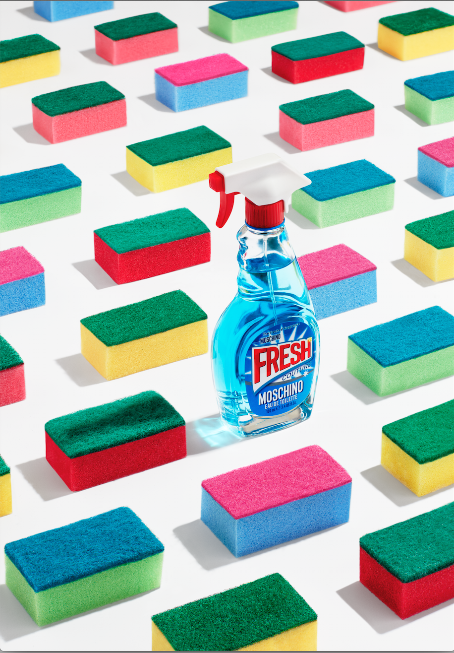 Instagram post: Perfume shaped like a glass-cleaner spray bottle among rows of colorful sponges
