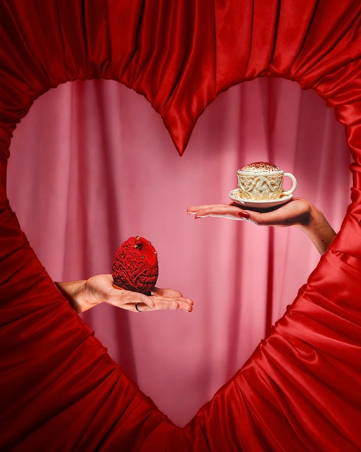 Valentine's Day creative ad: Two hands offering a red dessert and a cappuccino-style cup inside a satin heart