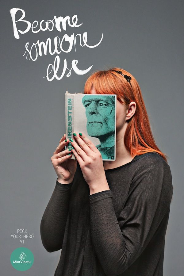 Red-haired woman holding a Frankenstein book cover over her face