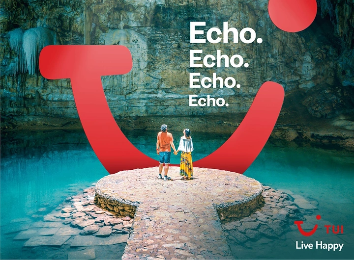 Travel creative ad: Couple on a stone platform in a cenote, framed by a giant red smile brand mark