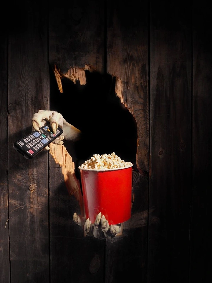 Cinemas & Movie Theatres creative ad: Hand bursts through wall with popcorn