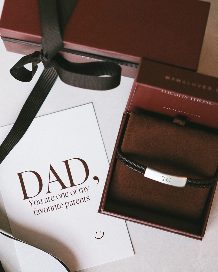 Father's Day creative ad: Engraved braided leather bracelet in an open burgundy gift box beside a Father's Day card