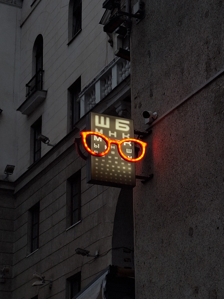 Opticians & Eye Care creative ad: Neon glasses over eye-chart shop sign