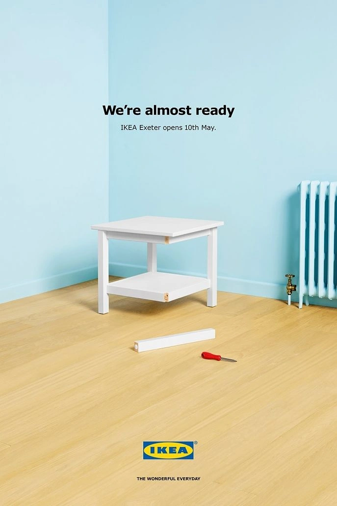 Furniture creative ad: Unfinished white side table missing one leg in an empty room