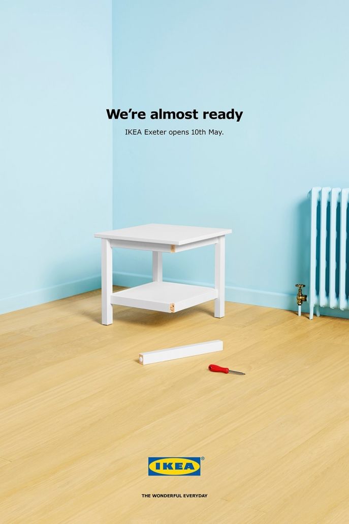 Poster: Unfinished white side table missing one leg in an empty room