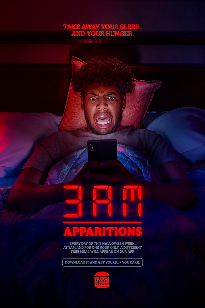 Halloween creative ad: Man in bed at night lit by his phone, staring in shock