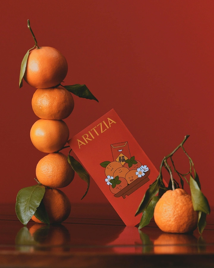 Lunar New Year creative ad: Stacked mandarins beside a branded red envelope