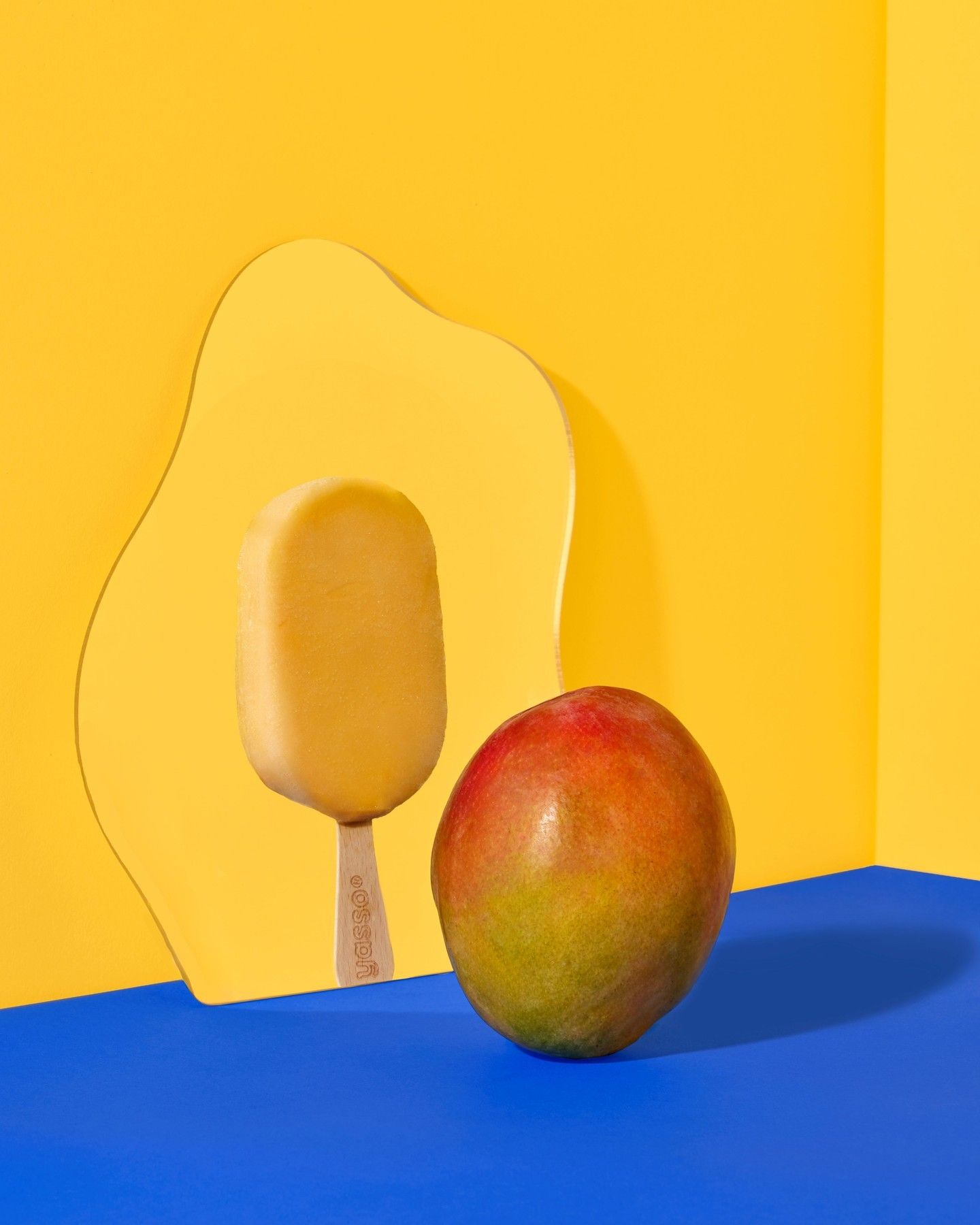Instagram post: Mango popsicle reflected in a wavy mirror beside a whole mango