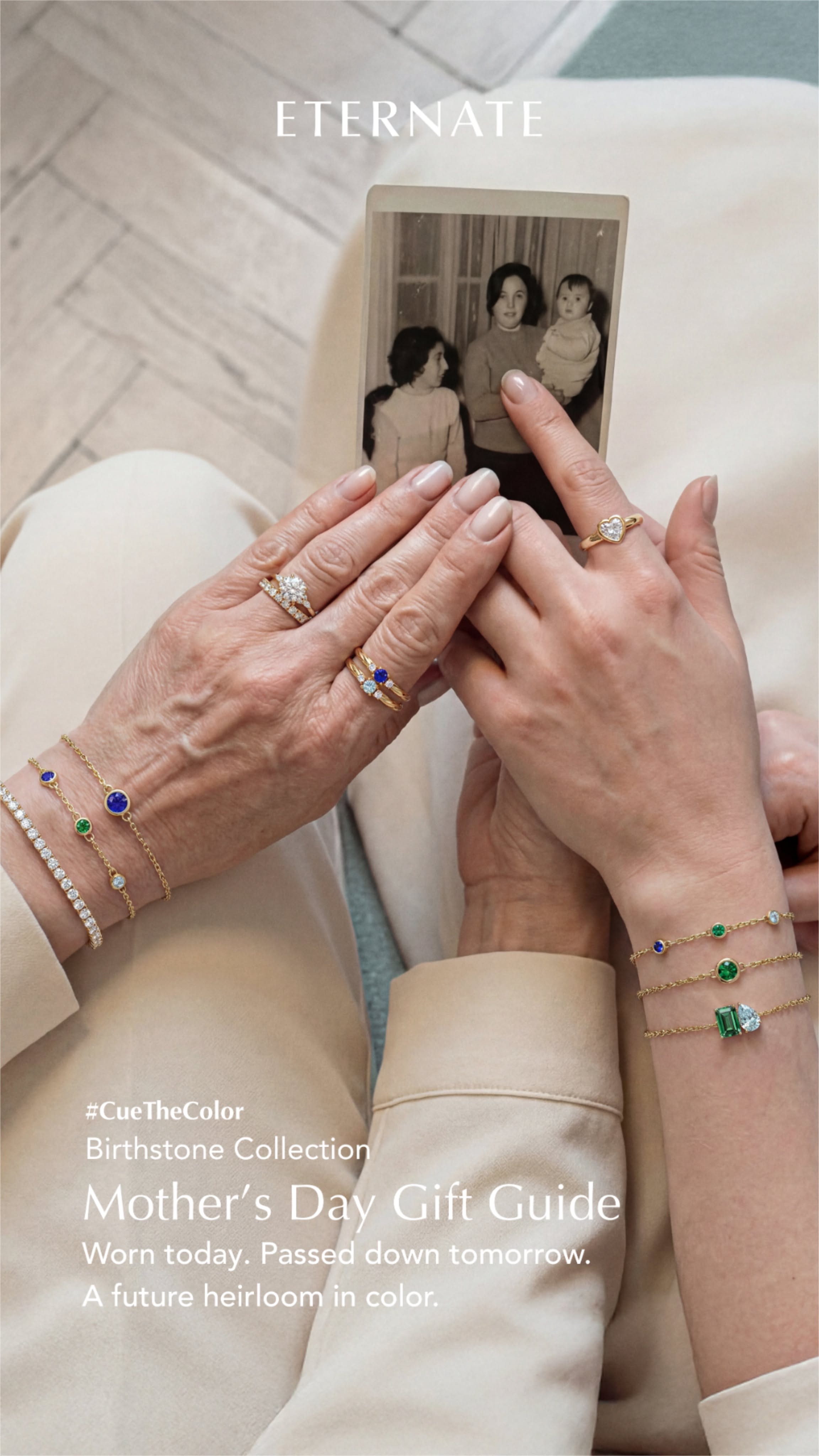 Older and younger hands wearing gemstone jewellery, holding an old family photo