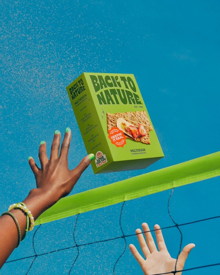Organic & Farm Produce creative ad: Cracker box flying over a volleyball net between two reaching hands