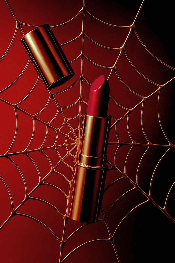 Halloween creative ad: Gold lipstick with red bullet on a gold spider web