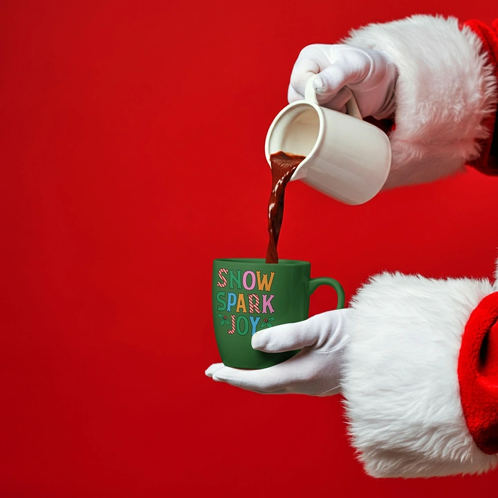 Christmas creative ad: Santa's gloved hands pouring hot chocolate into a green mug