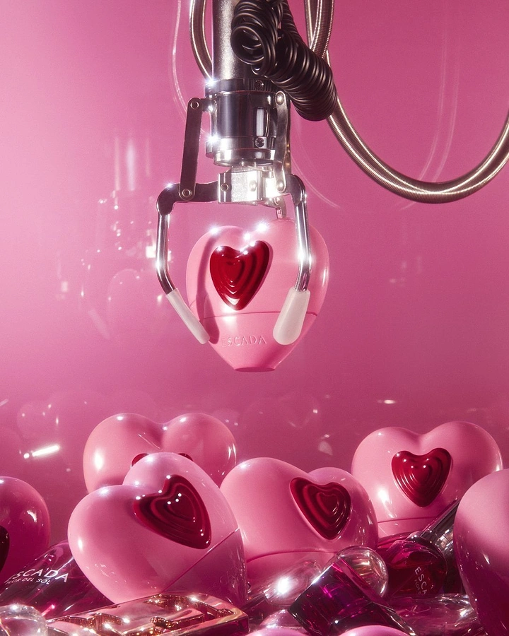 Valentine's Day creative ad: Claw-machine claw lifting a pink heart-shaped perfume bottle