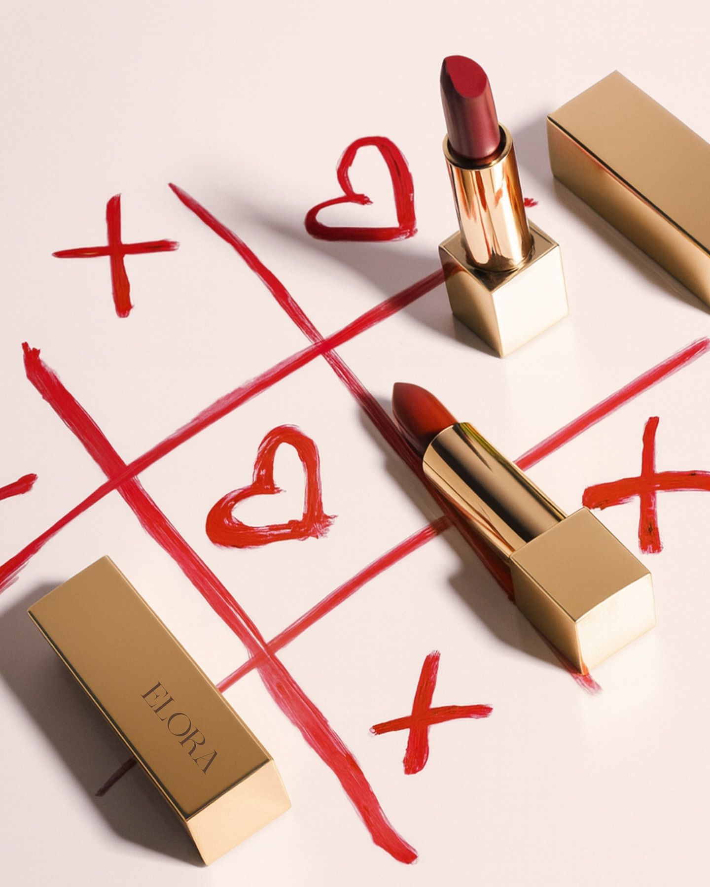 Valentine's Day Instagram post: Gold lipsticks on a lipstick-drawn tic-tac-toe of X's and hearts