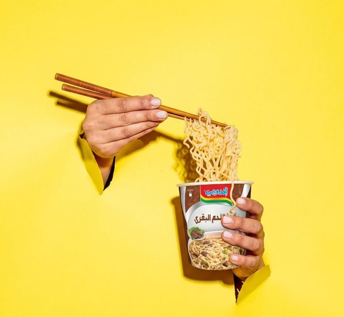 Instagram post: Surreal hands-through-yellow noodle presentation