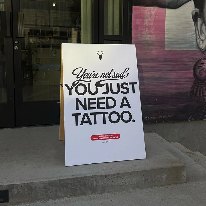 Tattoo Studios creative ad: Witty 'not sad, need a tattoo' sidewalk sign