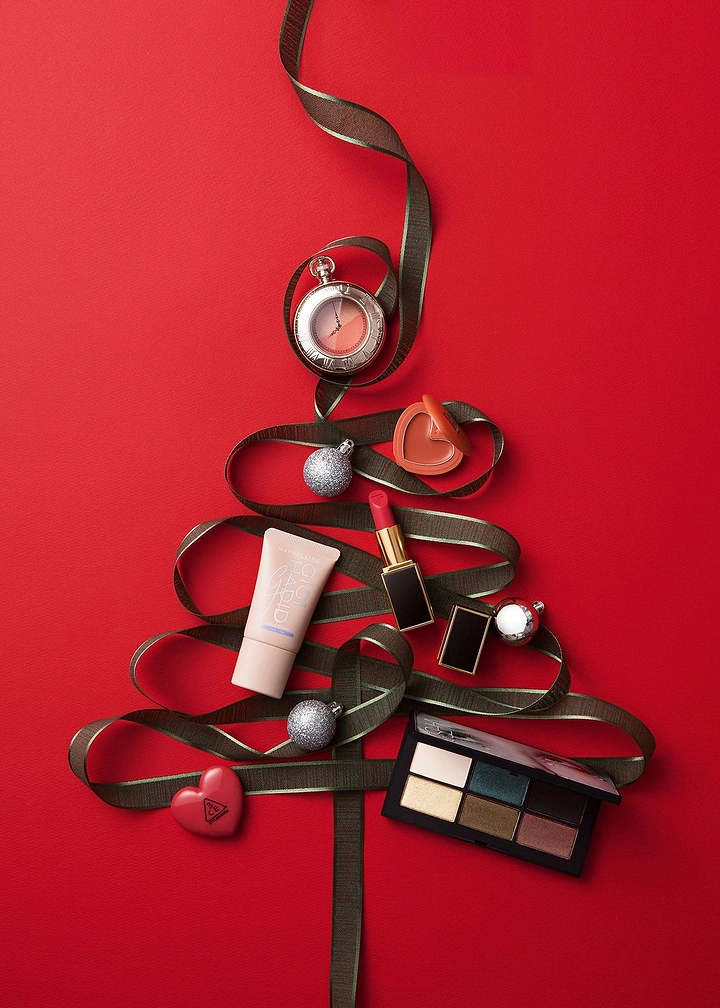 Christmas creative ad: Makeup products arranged on a ribbon Christmas tree