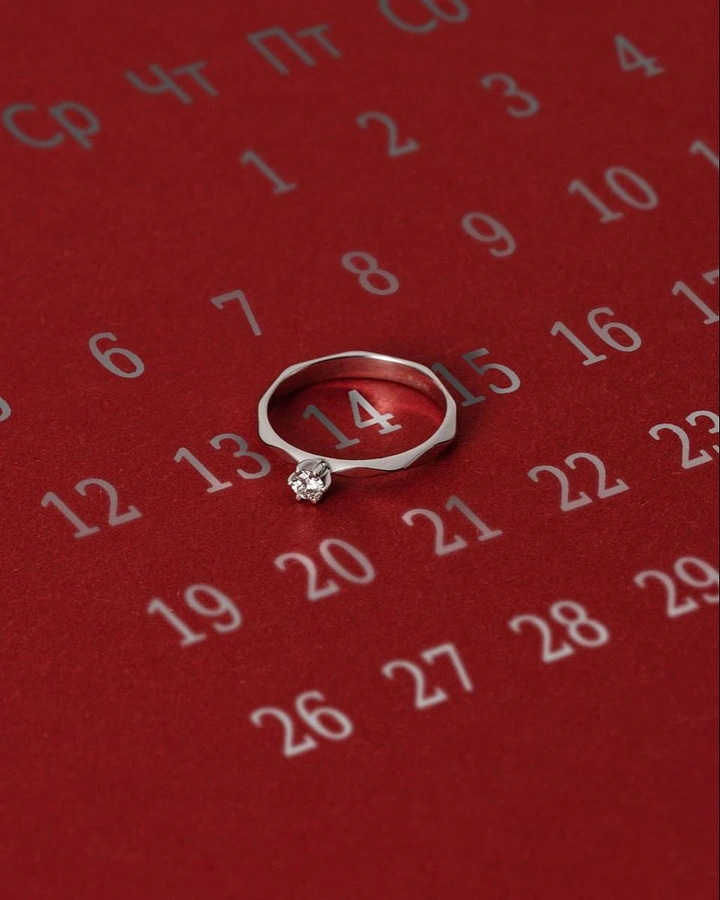 Valentine's Day creative ad: Diamond solitaire ring encircling the date 14 on a red calendar