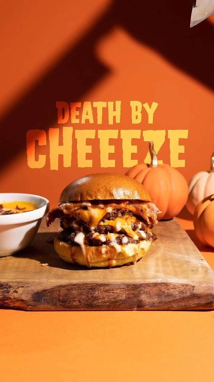 Halloween creative ad: Double cheeseburger dripping cheese on a rustic wooden board