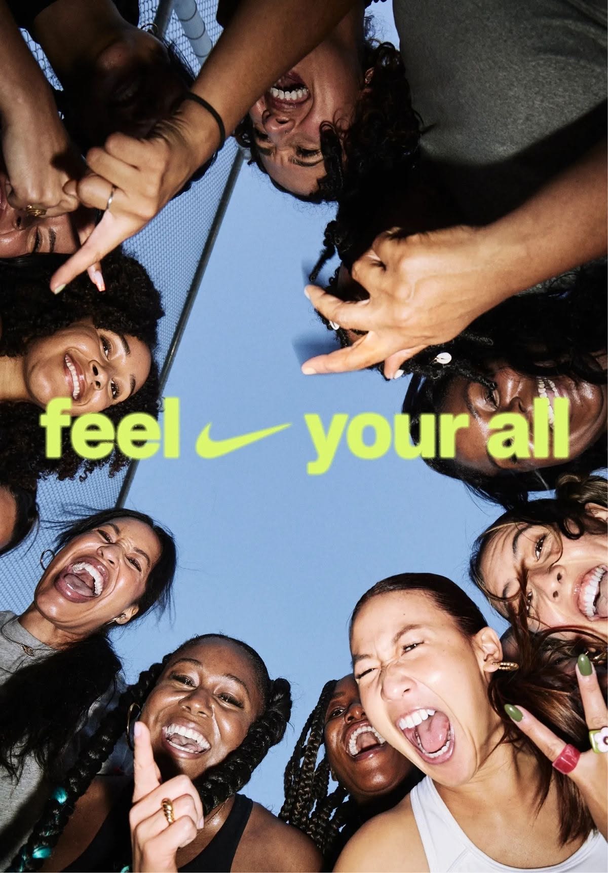 Circle of laughing, shouting women looking down at the camera against the sky