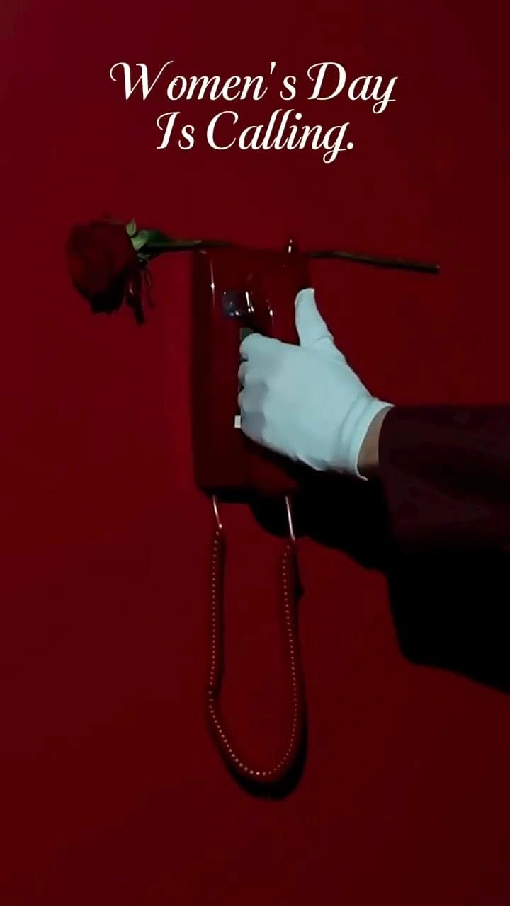 Women's Day creative ad: White-gloved hand lifting a red wall phone with a rose laid across it